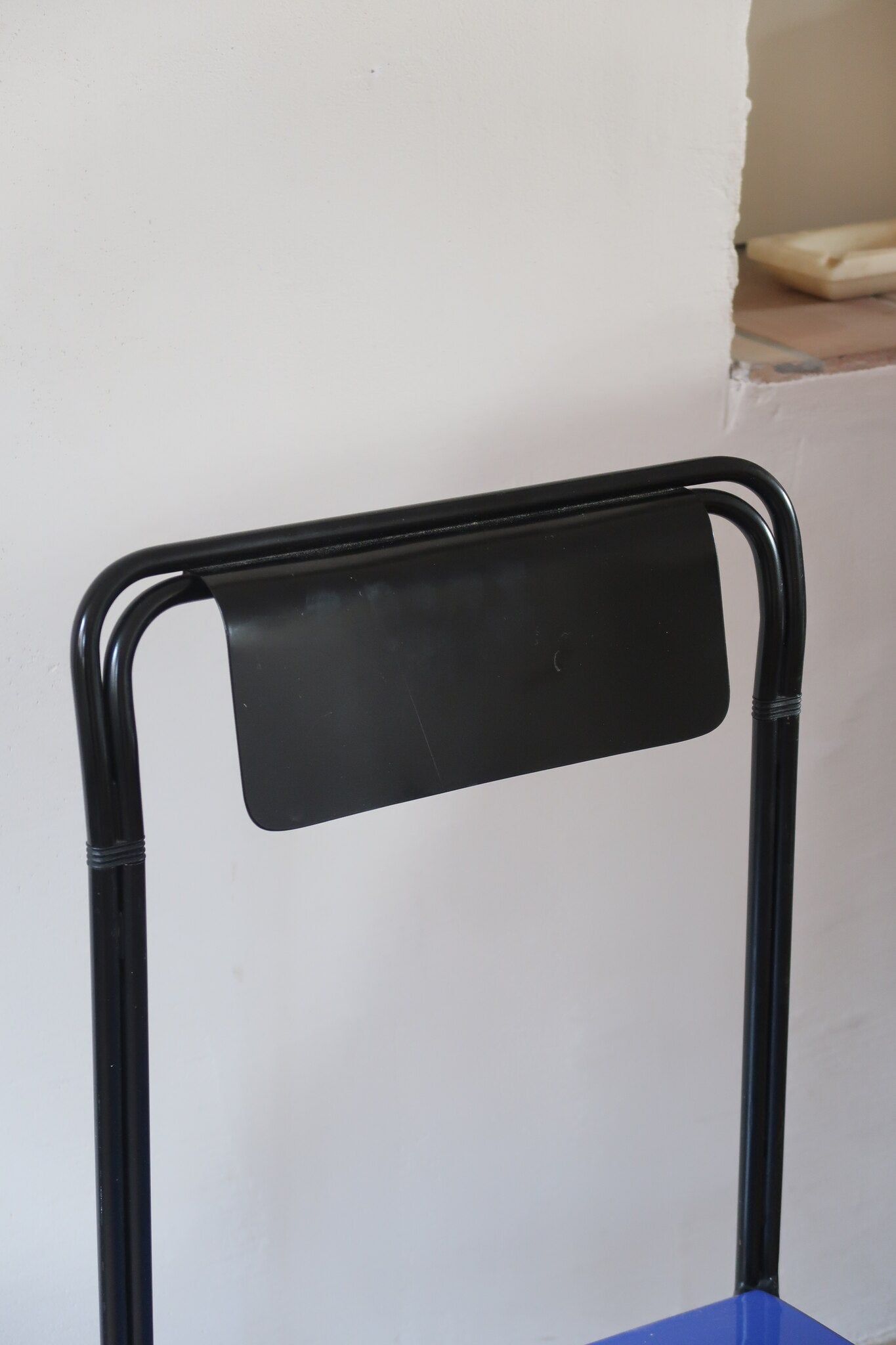 Chaise Kaa vintage par Francesco Soro années 80, tube d'acier laqué noir cintré d'un seul trait formant piétement et dossier, traverse en X au sol, assise en métal laqué bleu outremer