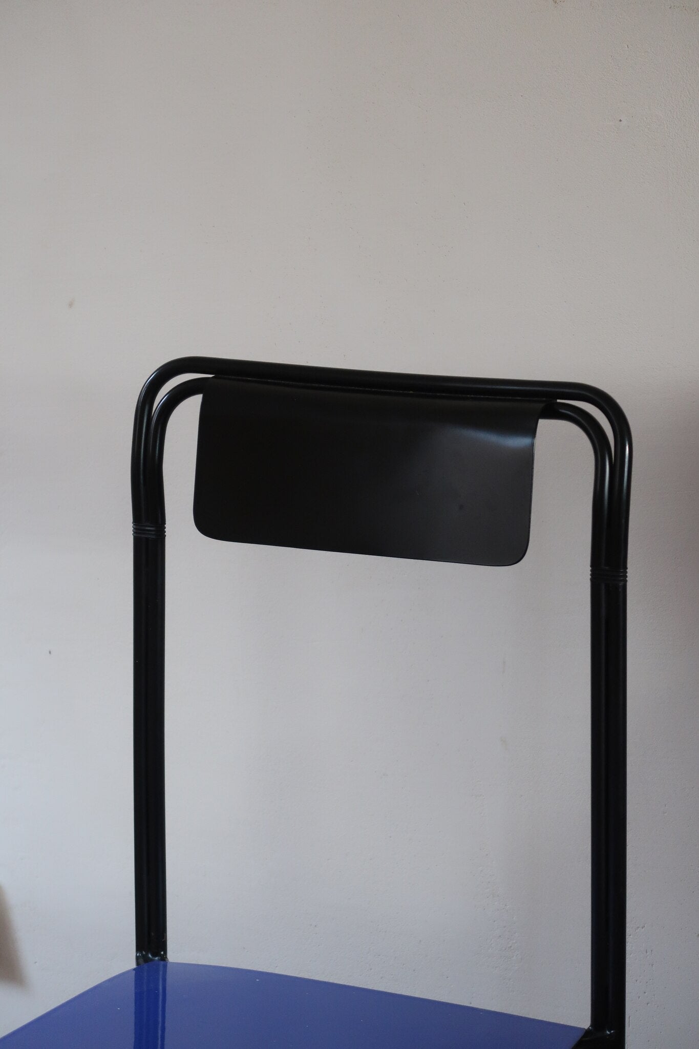Chaise Kaa vintage par Francesco Soro années 80, tube d'acier laqué noir cintré d'un seul trait formant piétement et dossier, traverse en X au sol, assise en métal laqué bleu outremer