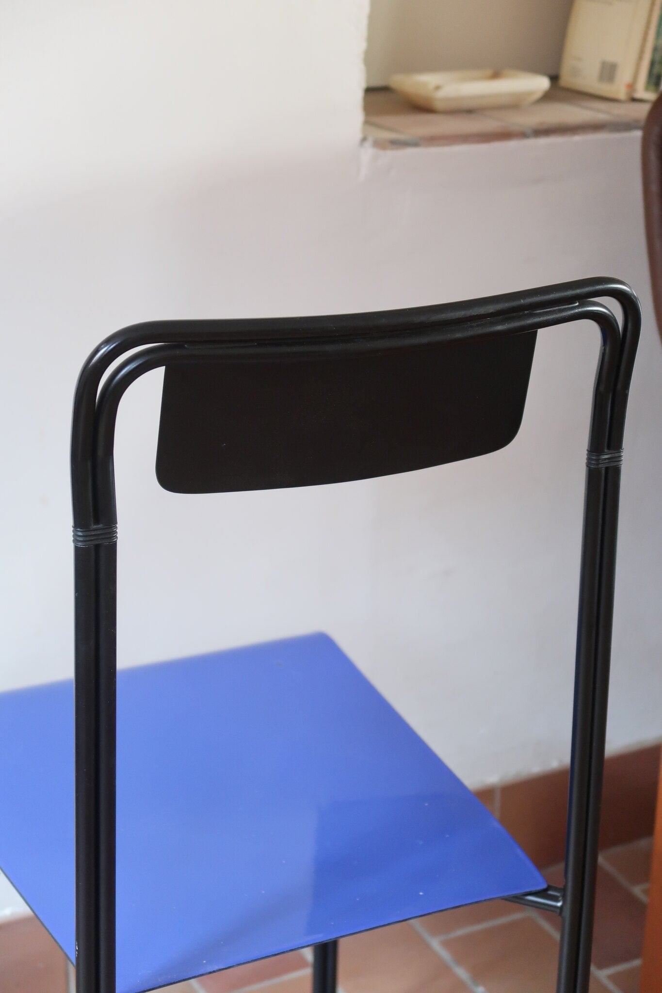 Chaise Kaa vintage par Francesco Soro années 80, tube d'acier laqué noir cintré d'un seul trait formant piétement et dossier, traverse en X au sol, assise en métal laqué bleu outremer
