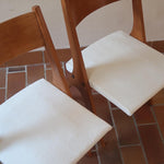 Deux chaises vintage en hêtre massif des années 50 avec assise en tissu bouclette clair, design épuré à la René-Jean Caillette, présentées seules et en mise en situation.