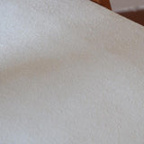 Deux chaises vintage en hêtre massif des années 50 avec assise en tissu bouclette clair, design épuré à la René-Jean Caillette, présentées seules et en mise en situation.