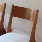 Deux chaises vintage en hêtre massif des années 50 avec assise en tissu bouclette clair, design épuré à la René-Jean Caillette, présentées seules et en mise en situation.