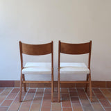 Deux chaises vintage en hêtre massif des années 50 avec assise en tissu bouclette clair, design épuré à la René-Jean Caillette, présentées seules et en mise en situation.