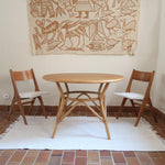 Deux chaises vintage en hêtre massif des années 50 avec assise en tissu bouclette clair, design épuré à la René-Jean Caillette, présentées seules et en mise en situation.