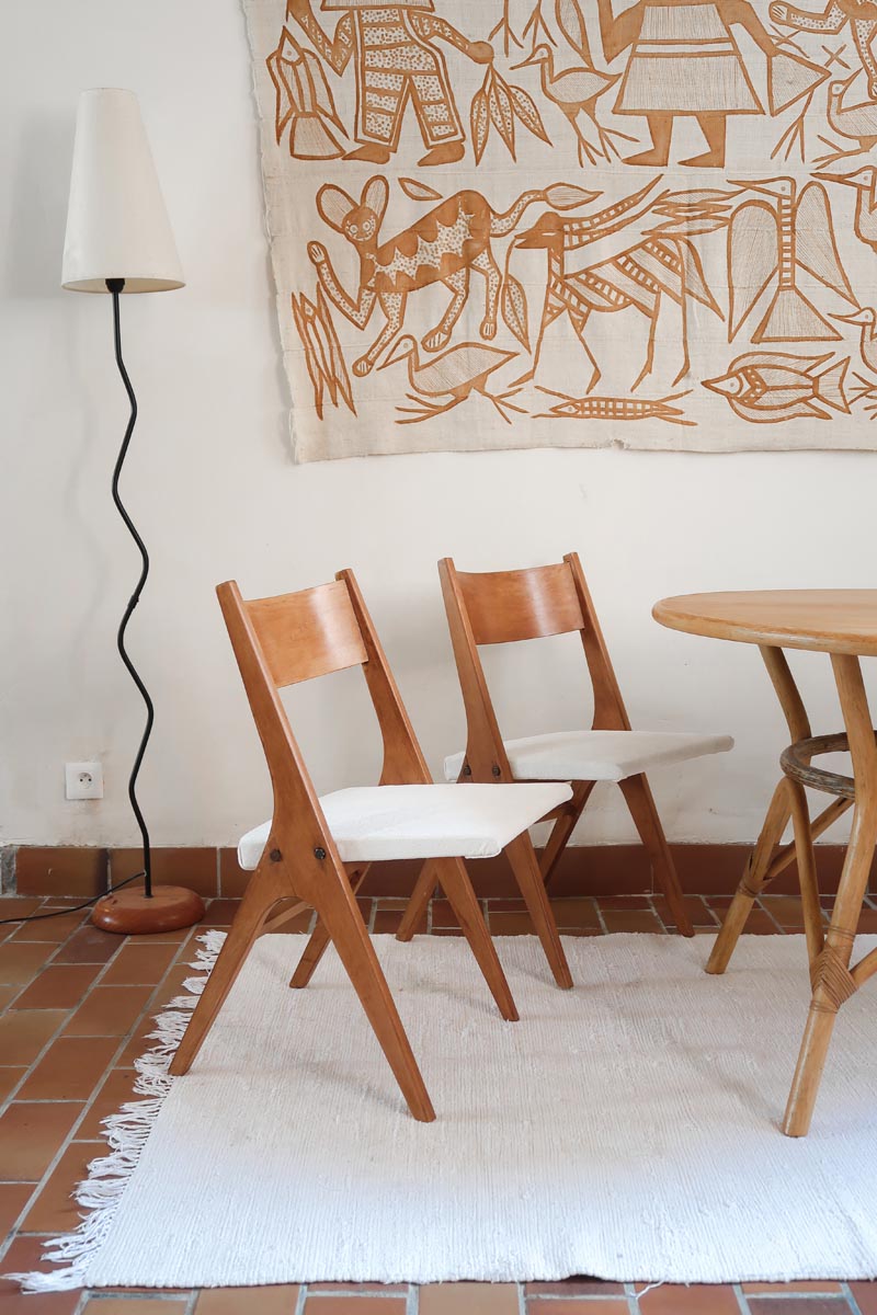 Deux chaises vintage en hêtre massif des années 50 avec assise en tissu bouclette clair, design épuré à la René-Jean Caillette, présentées seules et en mise en situation.