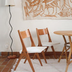 Deux chaises vintage en hêtre massif des années 50 avec assise en tissu bouclette clair, design épuré à la René-Jean Caillette, présentées seules et en mise en situation.