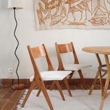 Deux chaises vintage en hêtre massif des années 50 avec assise en tissu bouclette clair, design épuré à la René-Jean Caillette, présentées seules et en mise en situation.