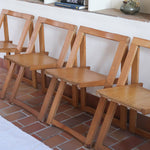 Quatre chaises pliantes en bois massif années 70 style Aldo Jacober avec dossier épais et assise à lattes.