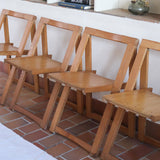 Quatre chaises pliantes en bois massif années 70 style Aldo Jacober avec dossier épais et assise à lattes.