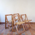 Quatre chaises pliantes en bois massif années 70 style Aldo Jacober avec dossier épais et assise à lattes.