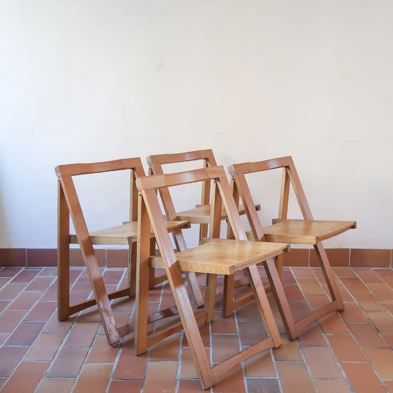 Quatre chaises pliantes en bois massif années 70 style Aldo Jacober avec dossier épais et assise à lattes.