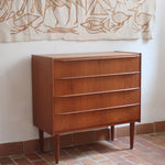 Commode danoise en teck des années 60 avec quatre tiroirs et lignes sobres typiques du mobilier scandinave mid-century.