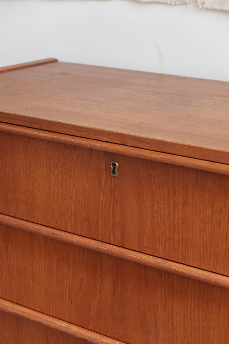 Commode danoise en teck des années 60 avec quatre tiroirs et lignes sobres typiques du mobilier scandinave mid-century.