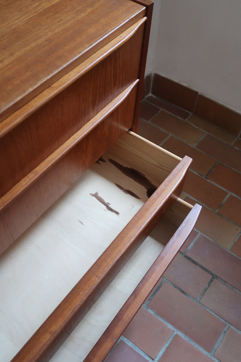 Commode danoise en teck des années 60 avec quatre tiroirs et lignes sobres typiques du mobilier scandinave mid-century.