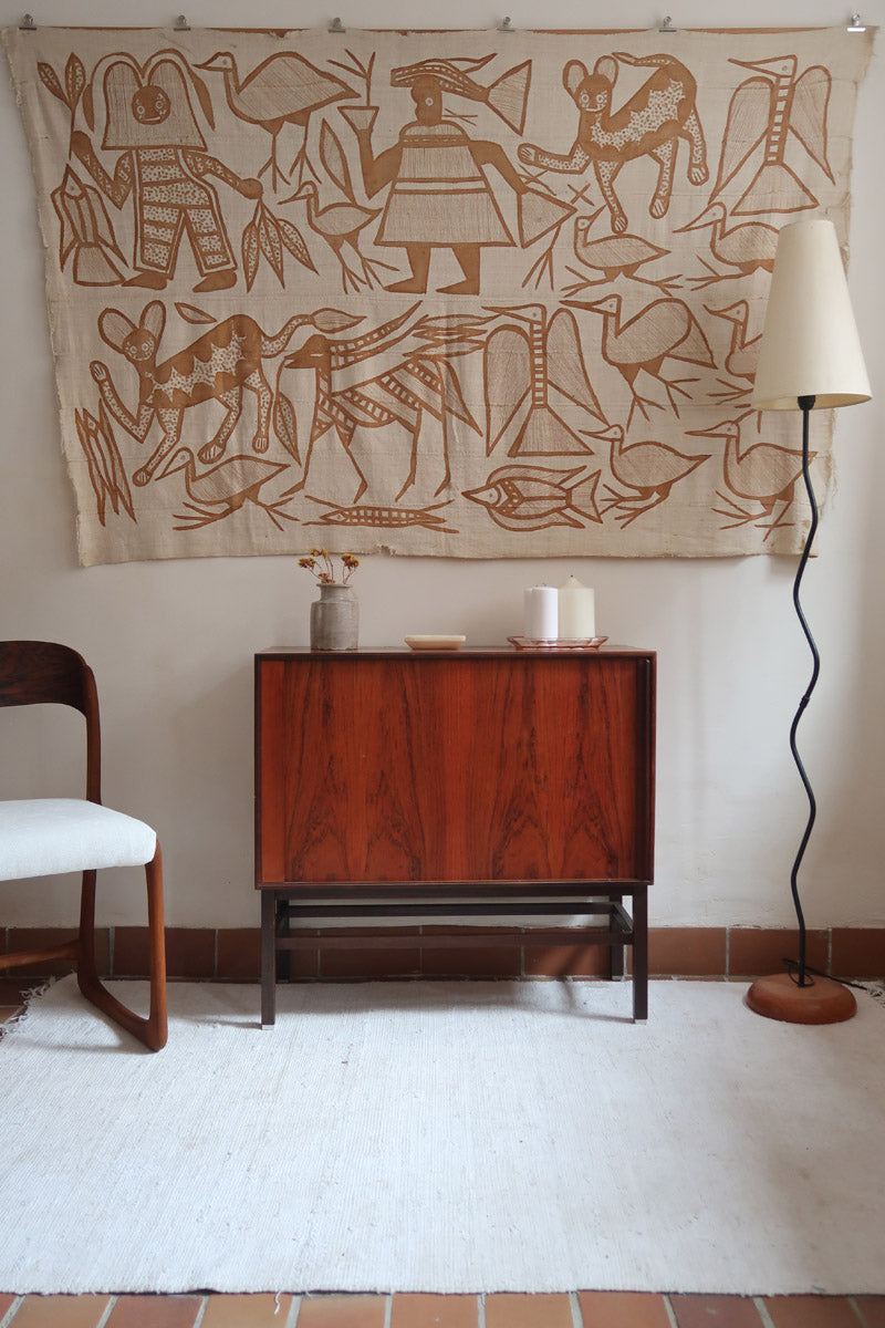 Buffet scandinave en teck années 60 à porte coulissante latérale, piètement foncé et intérieur ouvert.