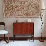 Buffet scandinave en teck années 60 à porte coulissante latérale, piètement foncé et intérieur ouvert.