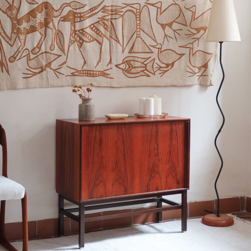 Buffet scandinave en teck années 60 à porte coulissante latérale, piètement foncé et intérieur ouvert.