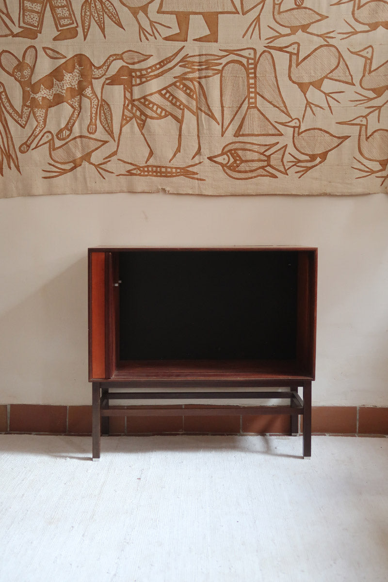 Buffet scandinave en teck années 60 à porte coulissante latérale, piètement foncé et intérieur ouvert.