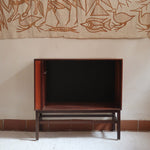Buffet scandinave en teck années 60 à porte coulissante latérale, piètement foncé et intérieur ouvert.