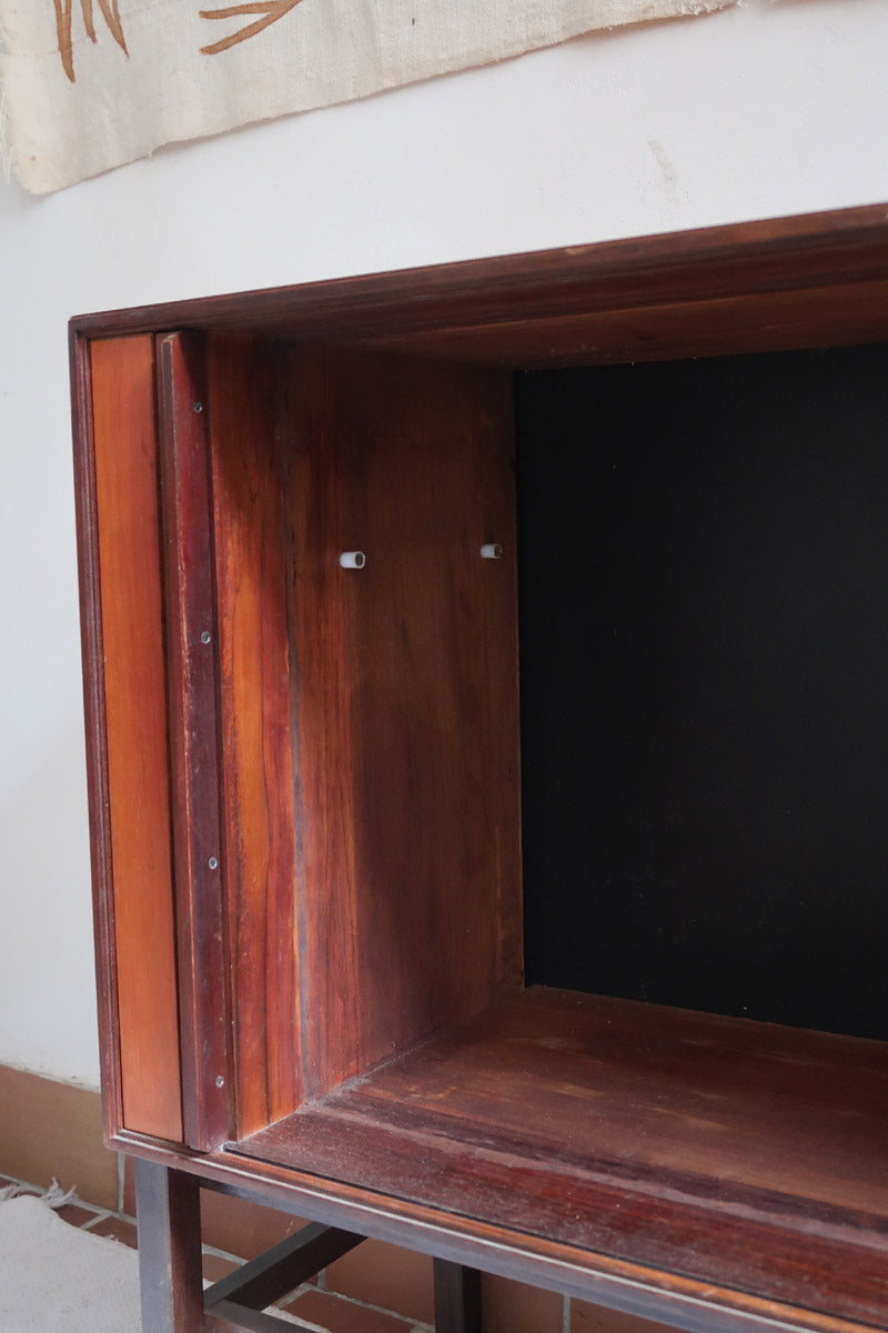 Buffet scandinave en teck années 60 à porte coulissante latérale, piètement foncé et intérieur ouvert.