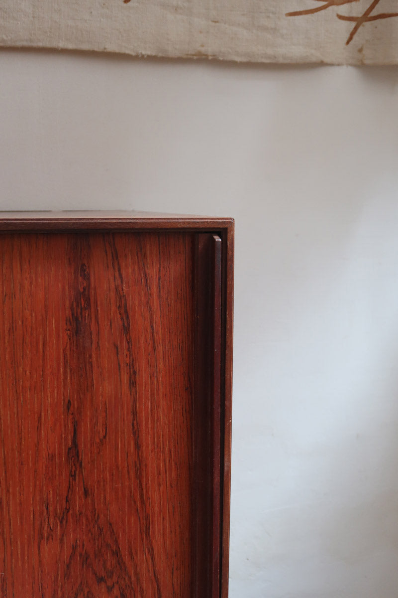 Buffet scandinave en teck années 60 à porte coulissante latérale, piètement foncé et intérieur ouvert.