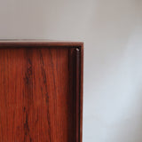 Buffet scandinave en teck années 60 à porte coulissante latérale, piètement foncé et intérieur ouvert.