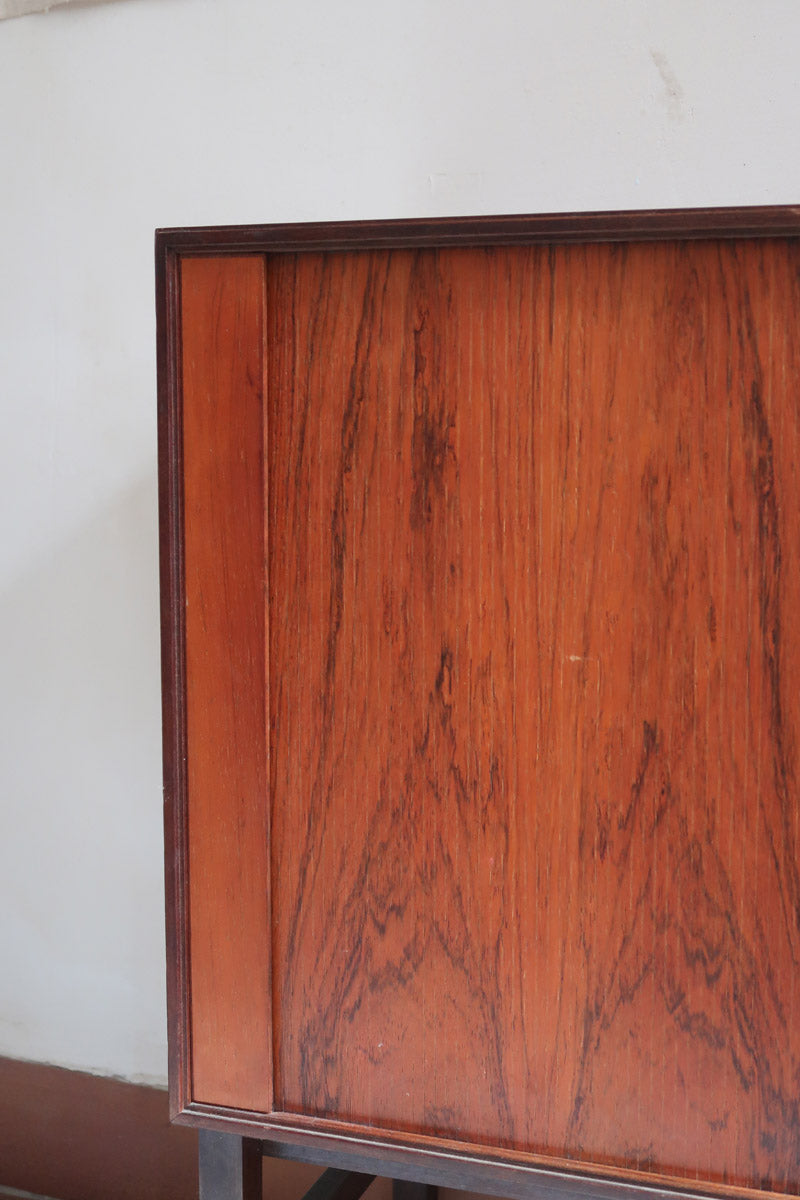 Buffet scandinave en teck années 60 à porte coulissante latérale, piètement foncé et intérieur ouvert.