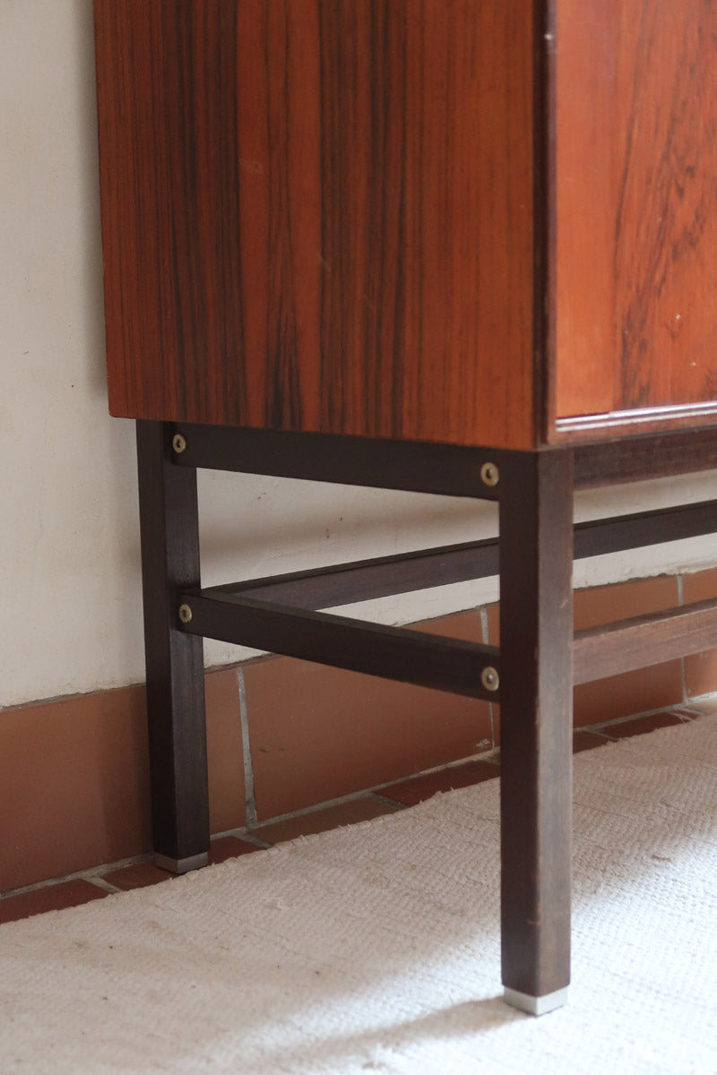 Buffet scandinave en teck années 60 à porte coulissante latérale, piètement foncé et intérieur ouvert.