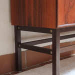 Buffet scandinave en teck années 60 à porte coulissante latérale, piètement foncé et intérieur ouvert.