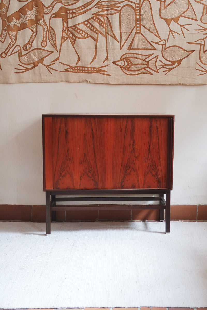 Buffet scandinave en teck années 60 à porte coulissante latérale, piètement foncé et intérieur ouvert.