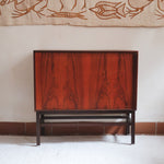 Buffet scandinave en teck années 60 à porte coulissante latérale, piètement foncé et intérieur ouvert.
