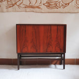 Buffet scandinave en teck années 60 à porte coulissante latérale, piètement foncé et intérieur ouvert.