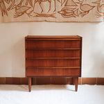 Commode vintage en teck des années 60 avec quatre tiroirs, façades galbées, poignées intégrées et pieds compas.