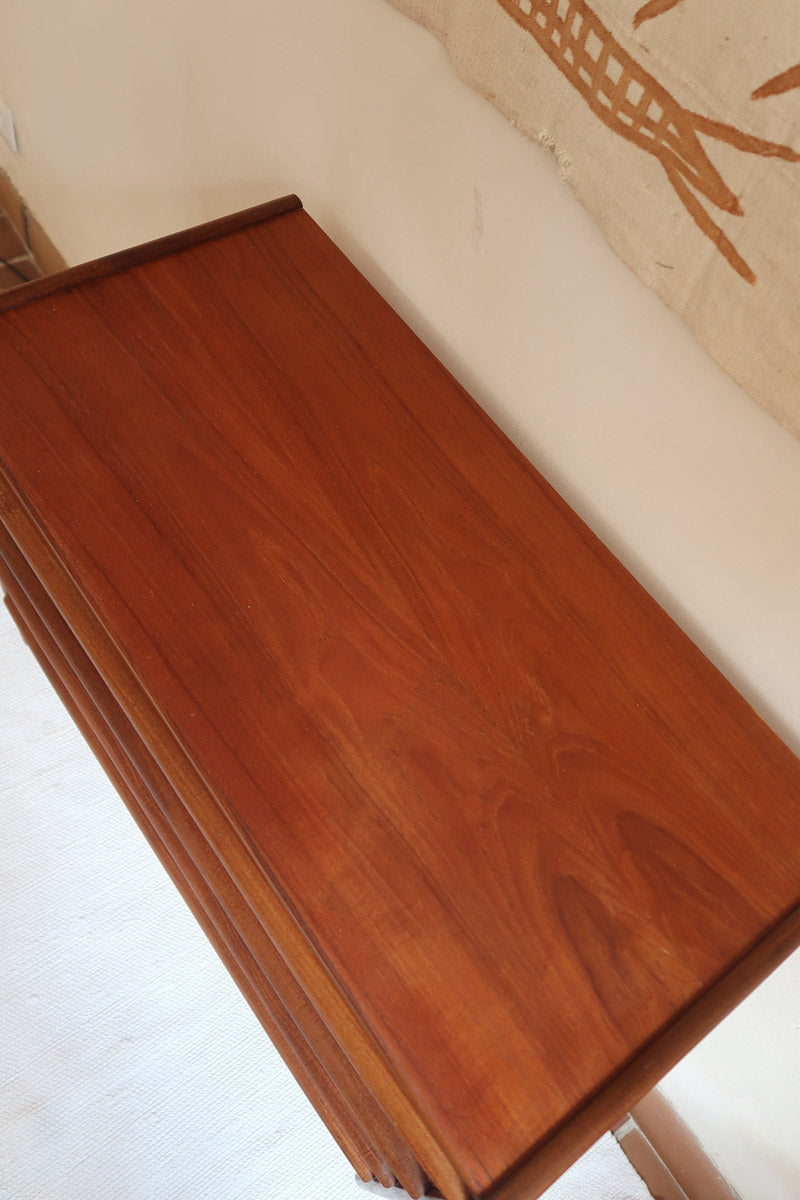 Commode vintage en teck des années 60 avec quatre tiroirs, façades galbées, poignées intégrées et pieds compas.