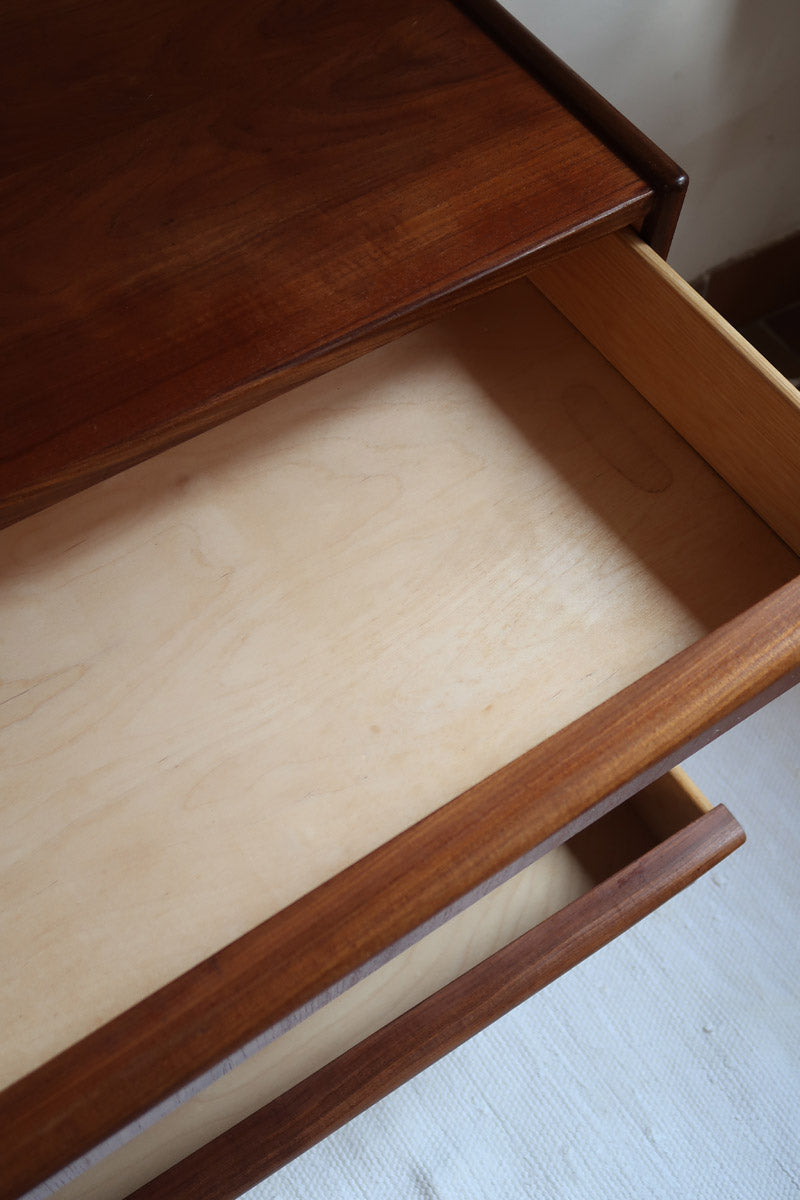 Commode vintage en teck des années 60 avec quatre tiroirs, façades galbées, poignées intégrées et pieds compas.