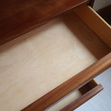 Commode vintage en teck des années 60 avec quatre tiroirs, façades galbées, poignées intégrées et pieds compas.
