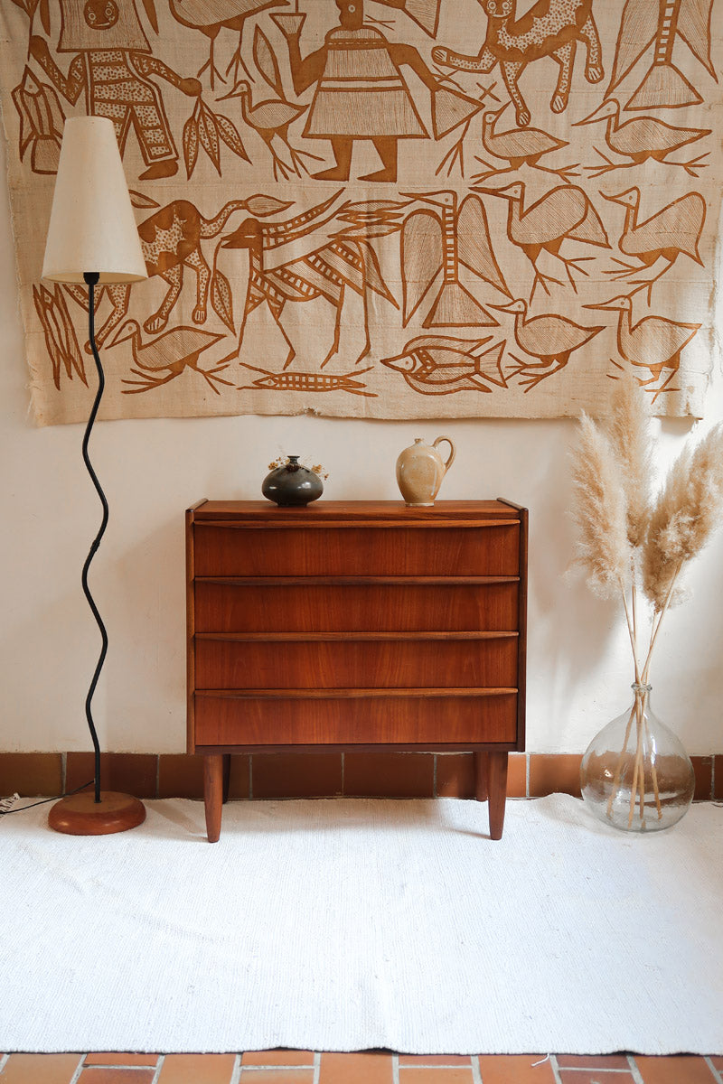 Commode vintage en teck des années 60 avec quatre tiroirs, façades galbées, poignées intégrées et pieds compas.