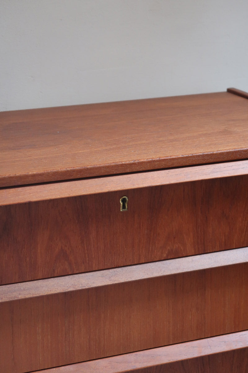 Commode scandinave en teck années 60 à trois tiroirs avec façade galbée et pieds compas.