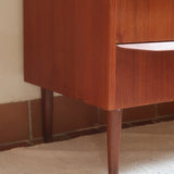 Commode scandinave en teck années 60 à trois tiroirs avec façade galbée et pieds compas.