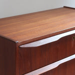 Commode scandinave en teck années 60 à quatre tiroirs et pieds compas, teinte chaude, design mid century.
