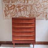 Commode scandinave en teck années 60 à cinq tiroirs, poignées sculptées intégrées et pieds compas.