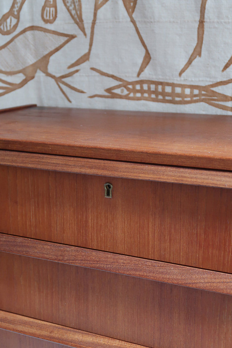 Commode scandinave en teck années 60 à cinq tiroirs, poignées sculptées intégrées et pieds compas.