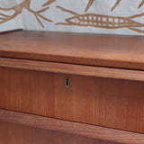 Commode scandinave en teck années 60 à cinq tiroirs, poignées sculptées intégrées et pieds compas.
