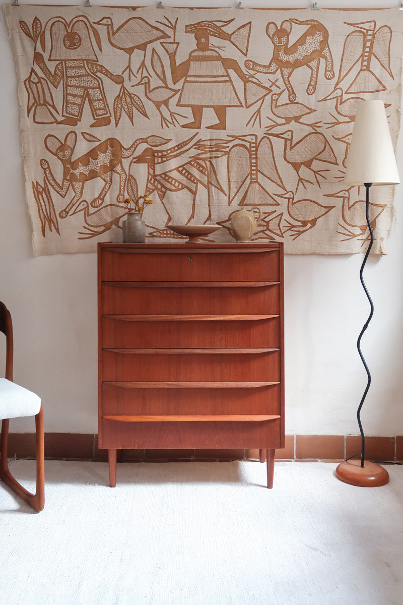 Commode scandinave en teck années 60 à cinq tiroirs, poignées sculptées intégrées et pieds compas.