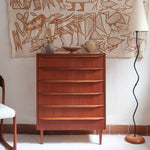Commode scandinave en teck années 60 à cinq tiroirs, poignées sculptées intégrées et pieds compas.