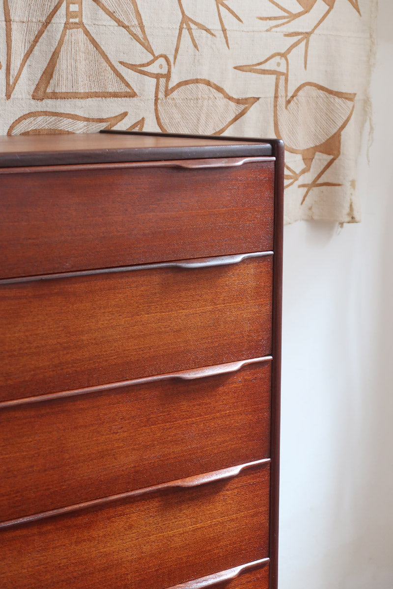 Commode haute scandinave en teck années 60 à six tiroirs avec poignées intégrées et piètement fuselé.