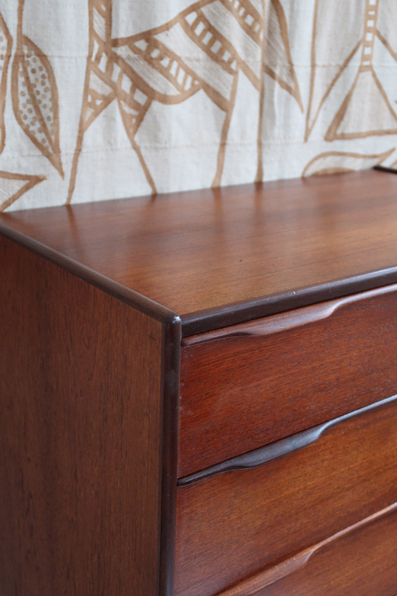 Commode haute scandinave en teck années 60 à six tiroirs avec poignées intégrées et piètement fuselé.