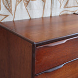 Commode haute scandinave en teck années 60 à six tiroirs avec poignées intégrées et piètement fuselé.