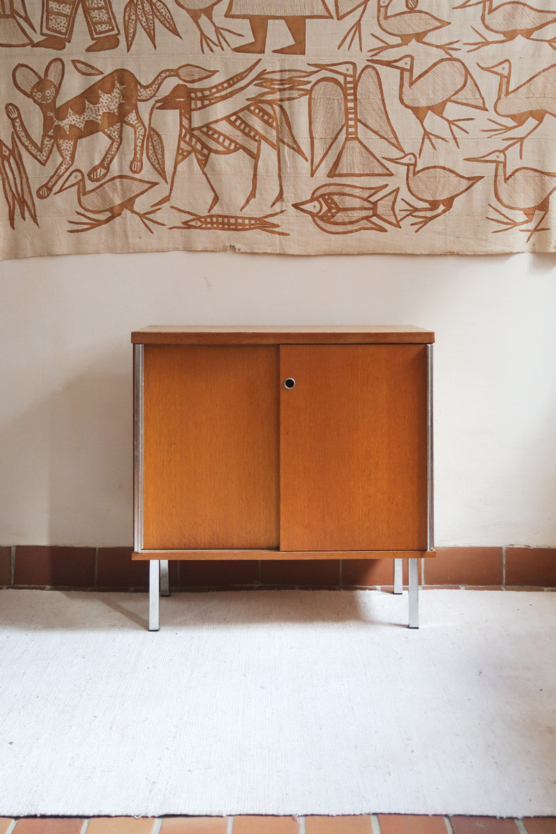 Meuble bas années 70 en bois avec piètement et montants en métal chromé, portes coulissantes et étagère intérieure.