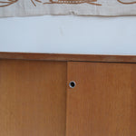 Meuble bas années 70 en bois avec piètement et montants en métal chromé, portes coulissantes et étagère intérieure.